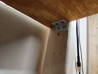 Under the shelf: the angle bracket goes as far forward as possible.