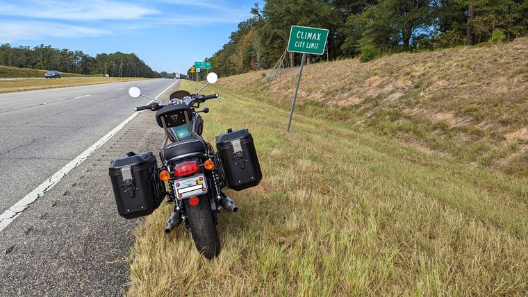Image: Motorcycle sitting on roadside near a sign saying Climax City Limits.
