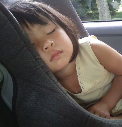 Image: A child that has falled asleep in the back seat.